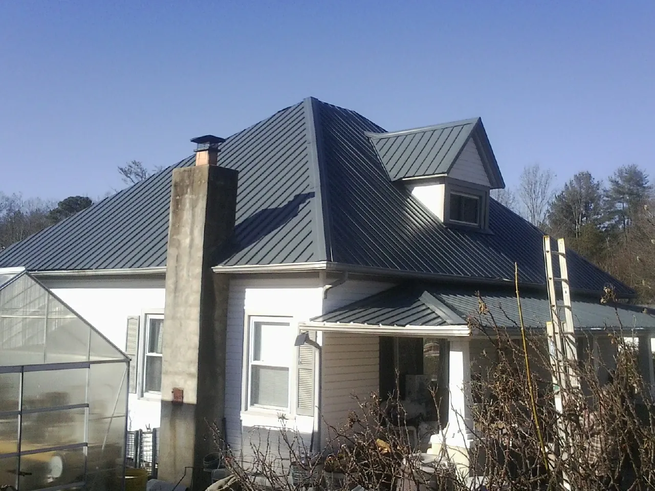 Dark blue standing seam metal roof on a white farmhouse with dormer — Slate & Tile Roof Repair by Roofing Brothers in Bloomingdale